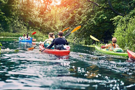 group of young people on kayak outing rafting down the river.